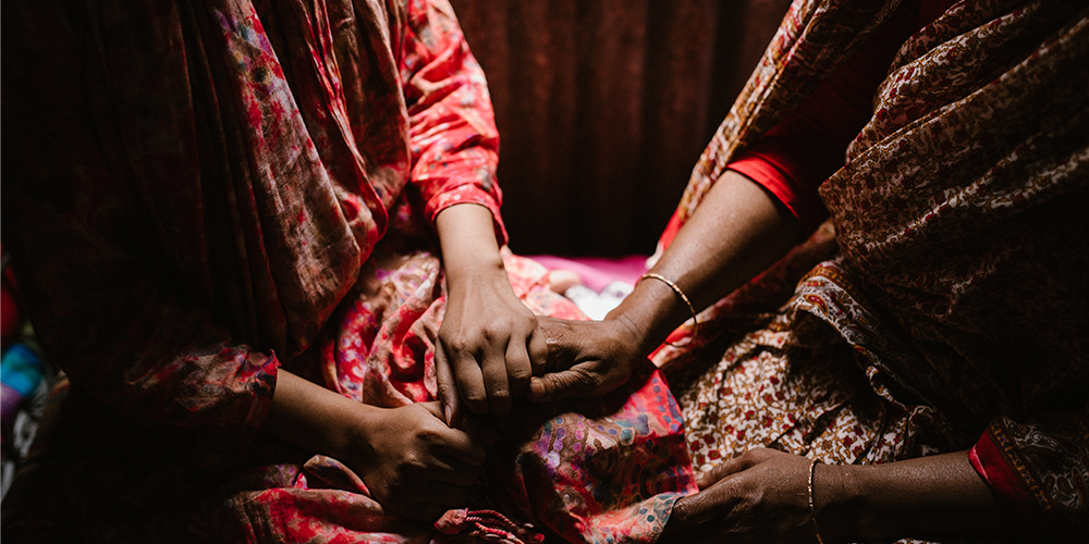 Asian women hold hands, pray